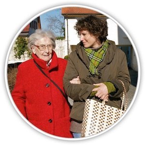 Eine Seniorin geht mit einer jüngeren Frau spazieren