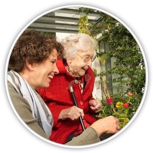 Eine Seniorin mit einer jüngeren Frau schauen sich rote Rosen bei einem Spaziergang an