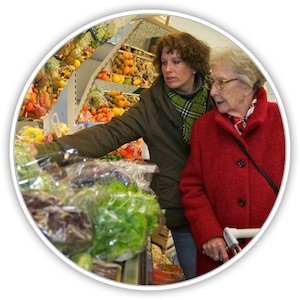 Eine Seniorin wird beim Einkaufen in einem Supermarkt von einer jüngeren Frau betreut