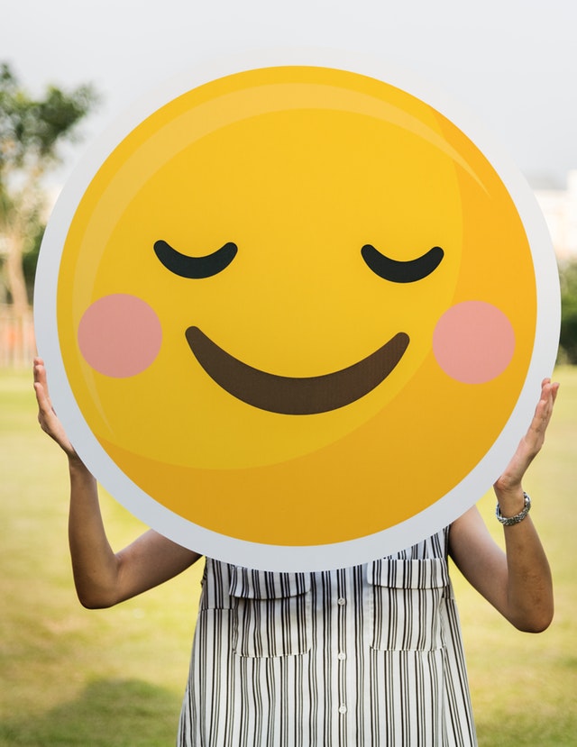Eine Frau mit einem lächelndem Smiley vor dem Gesicht